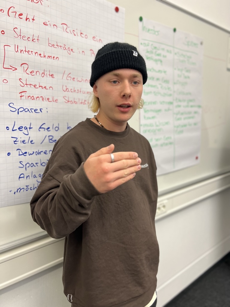 Azubi präsentiert vor Whiteboard – Investor, Sparer, Rendite