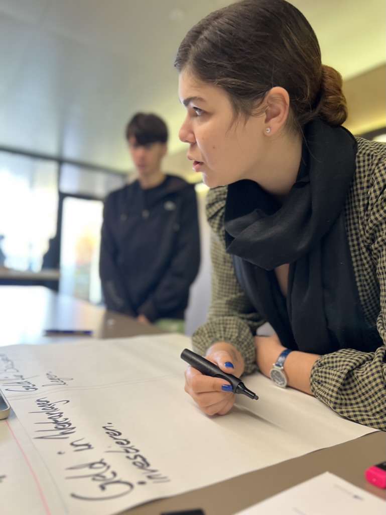 Azubi schreibt auf Plakat – Geld in Aktien investieren
